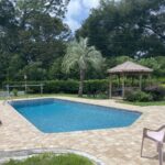 backyard pool after pool and pool deck renovation surrounded by lush landscaping