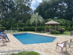 backyard pool after pool and pool deck renovation surrounded by lush landscaping