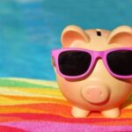 piggy bank wearing sunglasses with pool in the background.