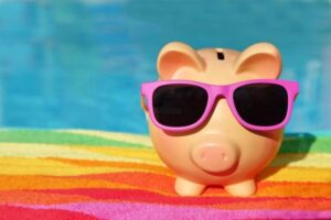 piggy bank wearing sunglasses with pool in the background.